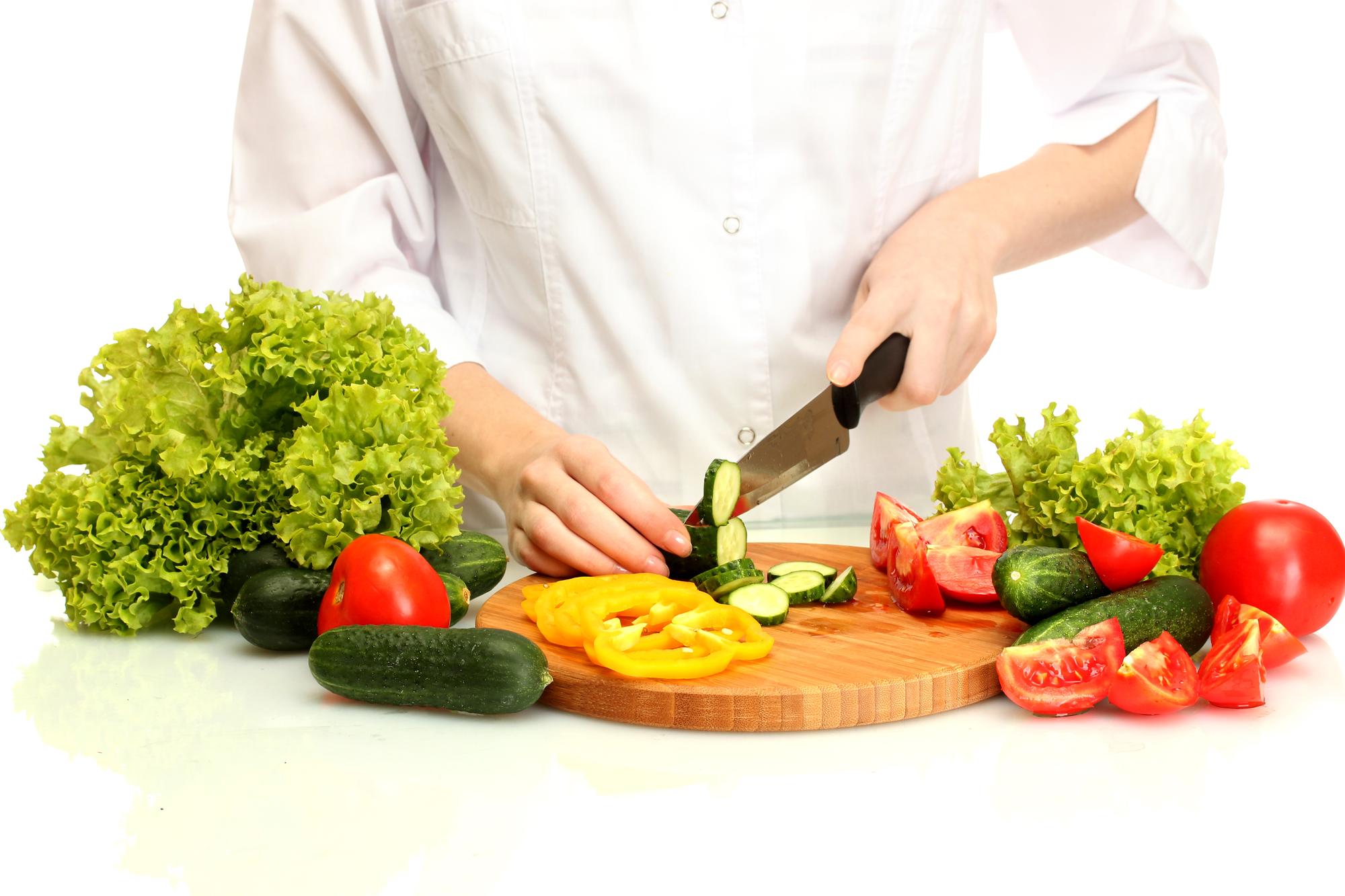 Instructor demonstrating knife skills with vegetables in a bright kitchen